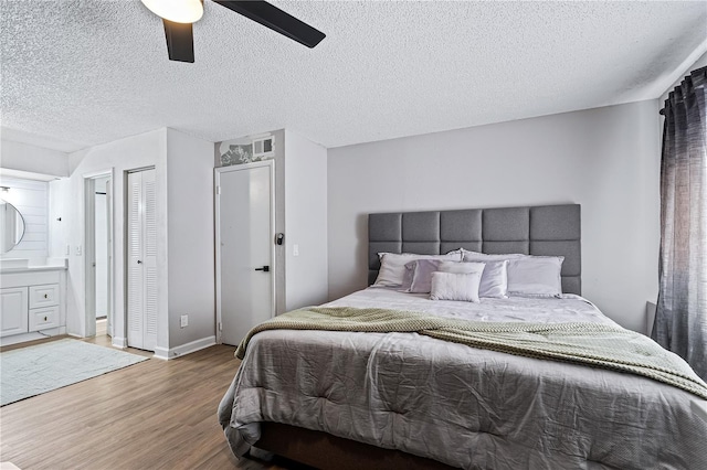 bedroom featuring a textured ceiling, ceiling fan, ensuite bath, and wood-type flooring