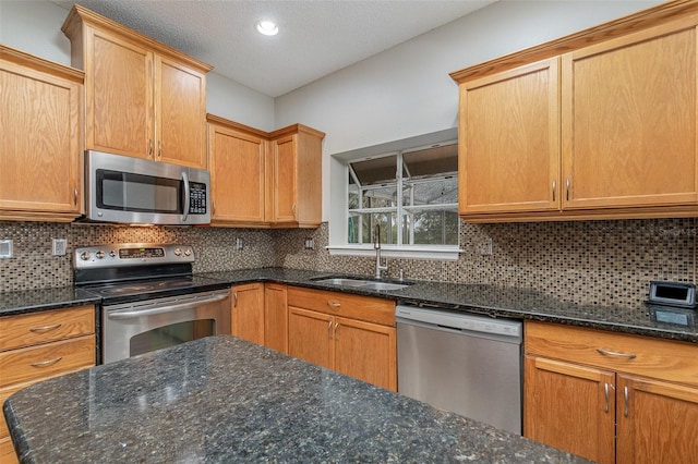 kitchen with stainless steel appliances, sink, dark stone countertops, and backsplash