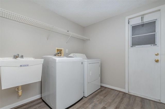 laundry area featuring hardwood / wood-style floors, sink, washer and dryer, and a textured ceiling