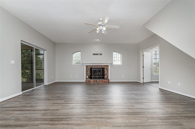 unfurnished living room featuring dark hardwood / wood-style floors, a brick fireplace, and a textured ceiling