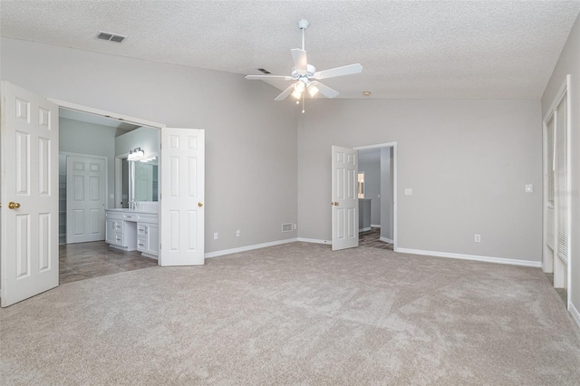 unfurnished bedroom featuring light carpet, connected bathroom, lofted ceiling, and ceiling fan