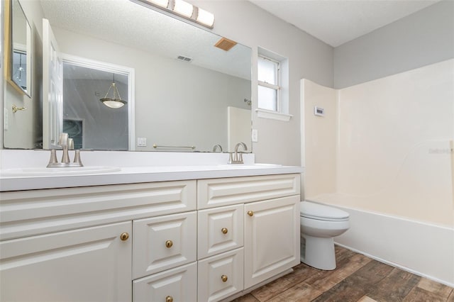 full bathroom with toilet, bathing tub / shower combination, a textured ceiling, vanity, and hardwood / wood-style flooring