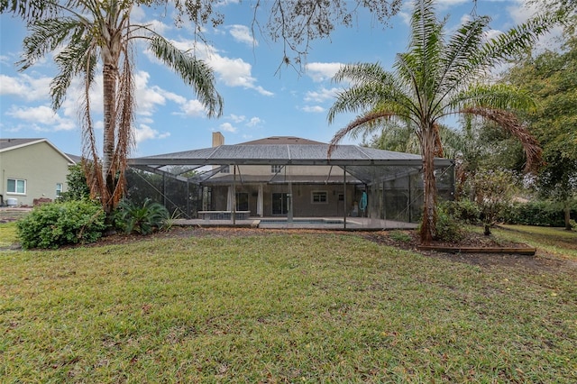 rear view of house featuring a pool, a yard, and a lanai