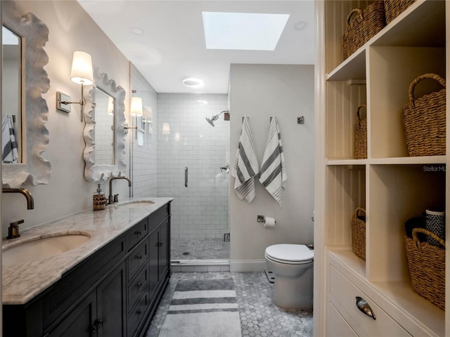 bathroom with vanity, a skylight, a shower with door, and toilet