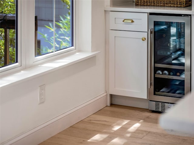 details with white cabinetry, beverage cooler, and light wood-type flooring