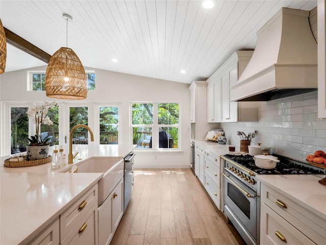 kitchen with premium range hood, stainless steel appliances, lofted ceiling with beams, decorative backsplash, and decorative light fixtures