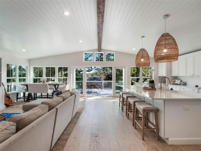 living room featuring sink, wood ceiling, light hardwood / wood-style flooring, and lofted ceiling with beams