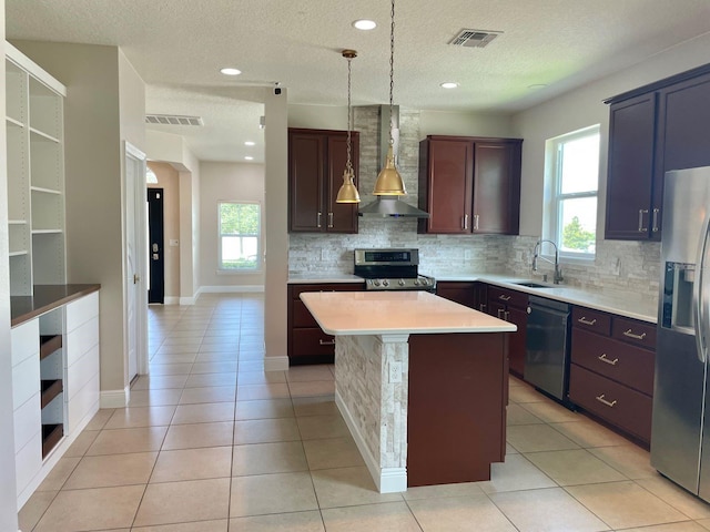 kitchen with wall chimney exhaust hood, visible vents, appliances with stainless steel finishes, and a sink