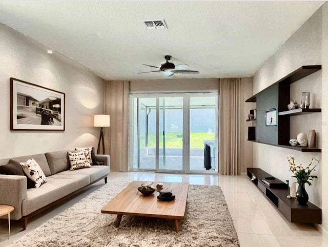 living room featuring a ceiling fan, visible vents, a textured ceiling, and light tile patterned floors