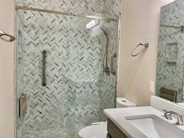 full bathroom with toilet, a textured wall, a shower stall, and vanity