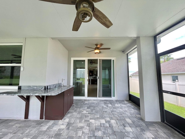 unfurnished sunroom with ceiling fan and a sink