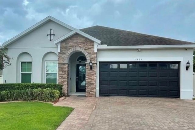 view of front facade featuring decorative driveway, an attached garage, and stucco siding