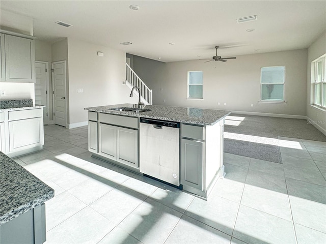 kitchen featuring ceiling fan, sink, stone countertops, stainless steel dishwasher, and a kitchen island with sink