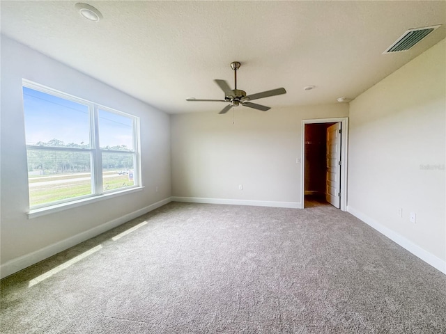 carpeted empty room featuring ceiling fan and a textured ceiling