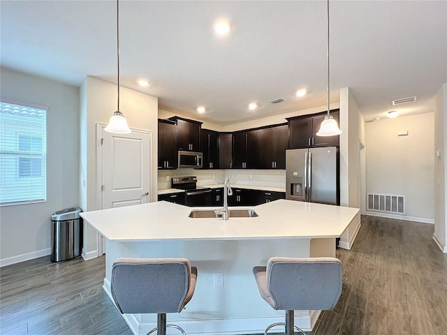 kitchen featuring a center island with sink, sink, decorative light fixtures, and appliances with stainless steel finishes