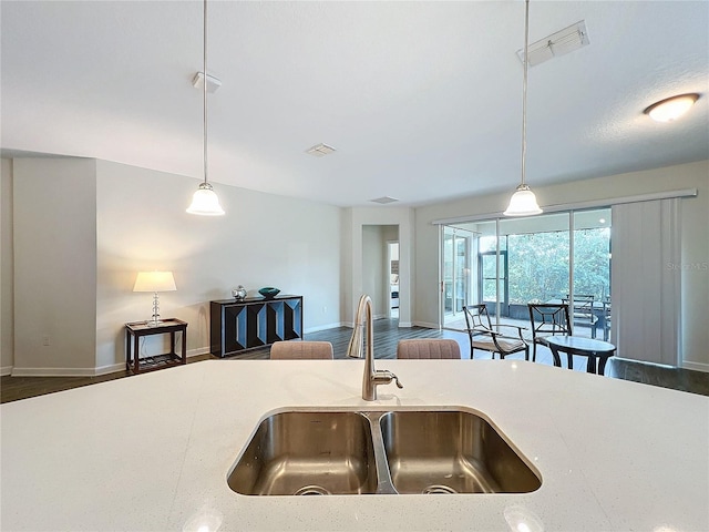 kitchen with dark hardwood / wood-style flooring, sink, light stone countertops, and hanging light fixtures