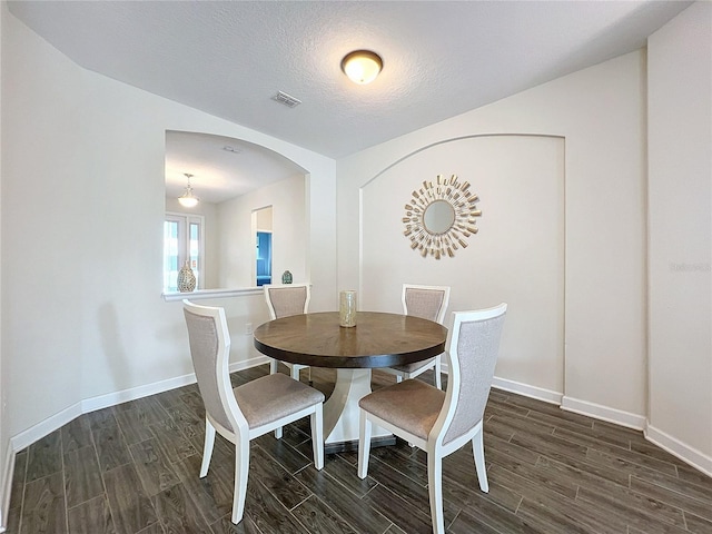 dining area featuring a textured ceiling and dark hardwood / wood-style flooring