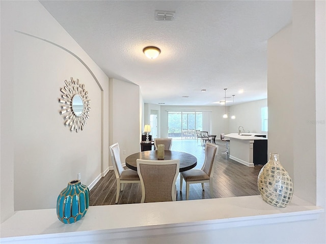 dining space featuring dark wood-type flooring, a textured ceiling, and sink