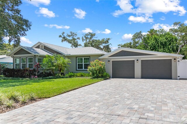 ranch-style home with a garage and a front lawn