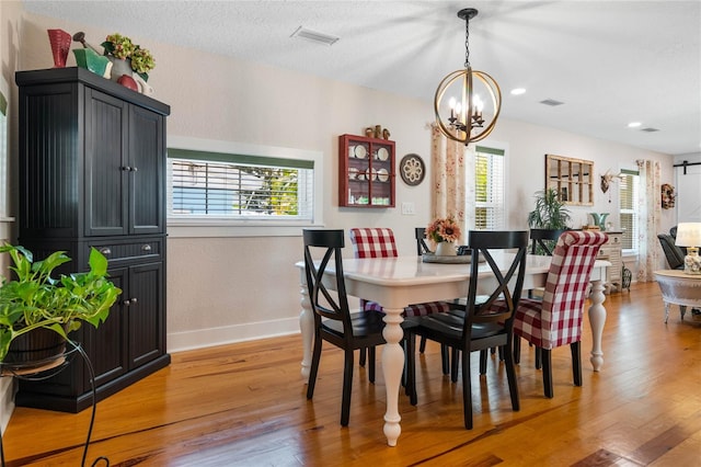 dining room with hardwood / wood-style floors, a textured ceiling, and an inviting chandelier