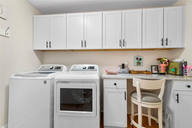 clothes washing area with cabinets and washing machine and clothes dryer