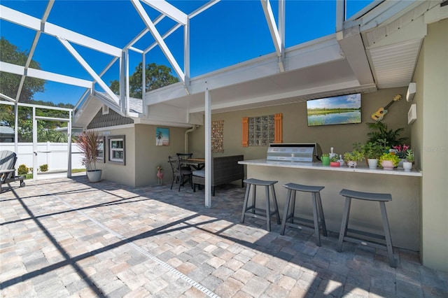 view of patio / terrace with exterior bar, glass enclosure, grilling area, and exterior kitchen