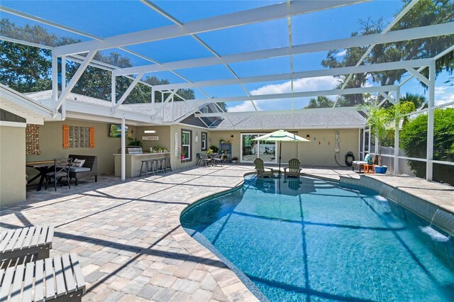 view of swimming pool with a lanai, pool water feature, a bar, and a patio