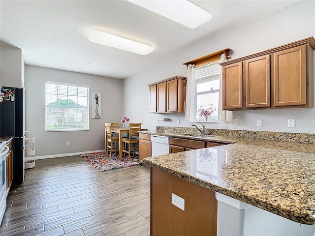 kitchen with sink, white appliances, light hardwood / wood-style floors, and stone counters