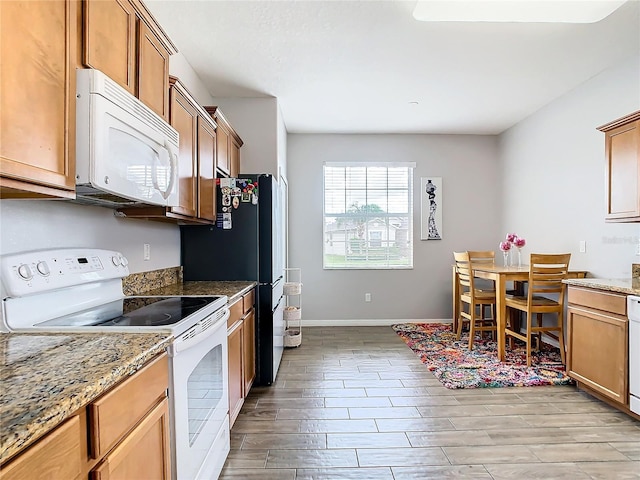 kitchen with light hardwood / wood-style flooring, white appliances, and stone counters