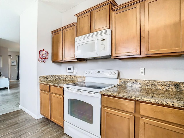 kitchen with white appliances, wood-type flooring, and stone counters