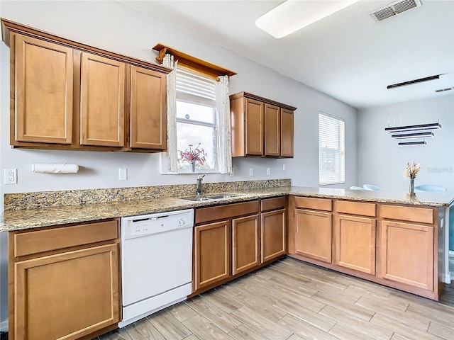 kitchen with white dishwasher, light hardwood / wood-style flooring, light stone countertops, sink, and kitchen peninsula