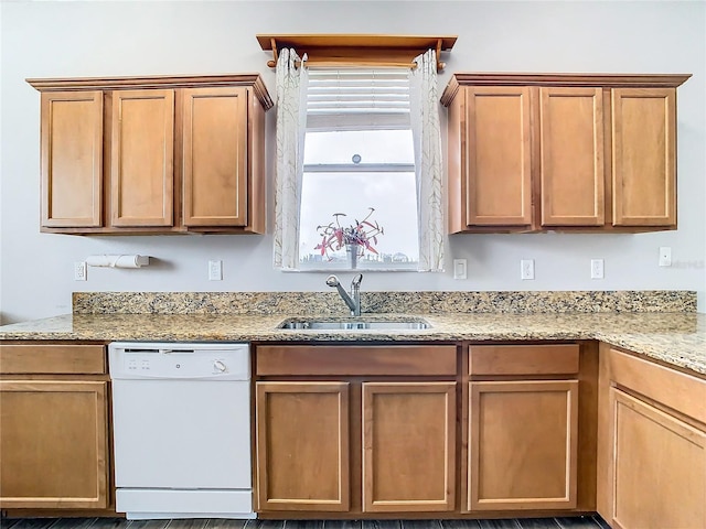 kitchen with white dishwasher, sink, and light stone countertops