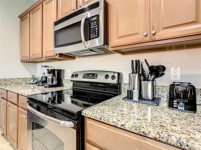 kitchen with light tile patterned floors, light stone countertops, appliances with stainless steel finishes, and light brown cabinets