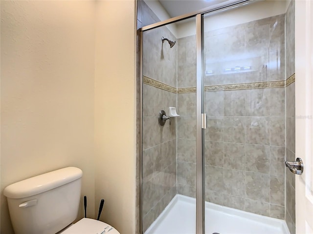 bathroom with a shower with shower door and toilet