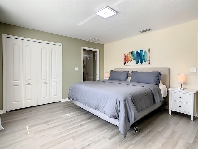 bedroom featuring a textured ceiling, a closet, and light hardwood / wood-style floors