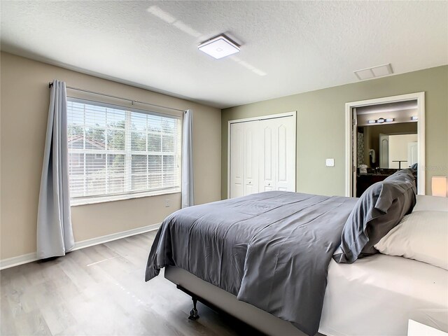 bedroom with a textured ceiling, light hardwood / wood-style flooring, and a closet