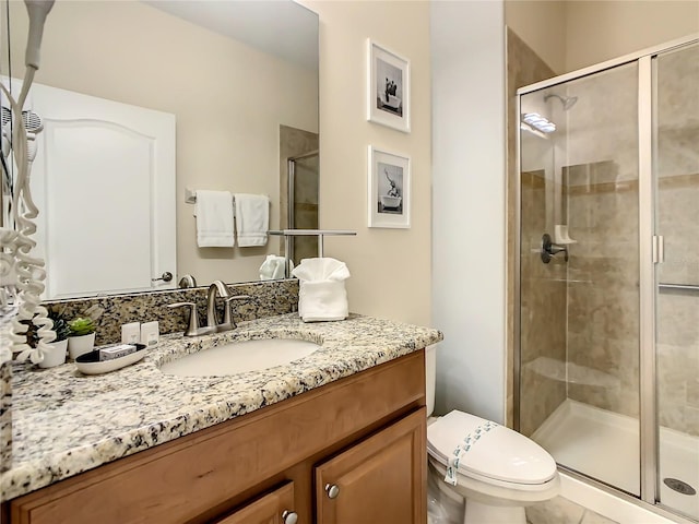 bathroom featuring a shower with door, vanity, and toilet