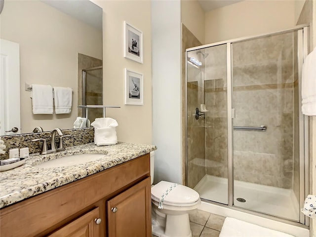 bathroom featuring tile patterned flooring, vanity, toilet, and a shower with shower door