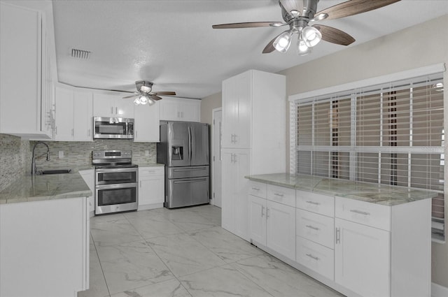 kitchen featuring tasteful backsplash, sink, ceiling fan, appliances with stainless steel finishes, and white cabinets