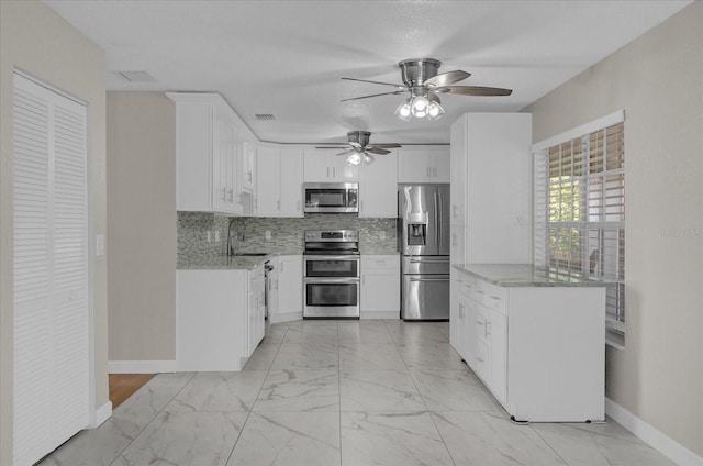 kitchen featuring white cabinets, appliances with stainless steel finishes, sink, ceiling fan, and tasteful backsplash