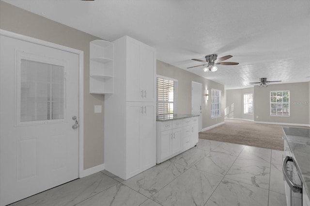 kitchen with light colored carpet, white cabinetry, light stone countertops, and ceiling fan