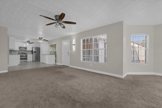 unfurnished living room with a textured ceiling, light colored carpet, and ceiling fan