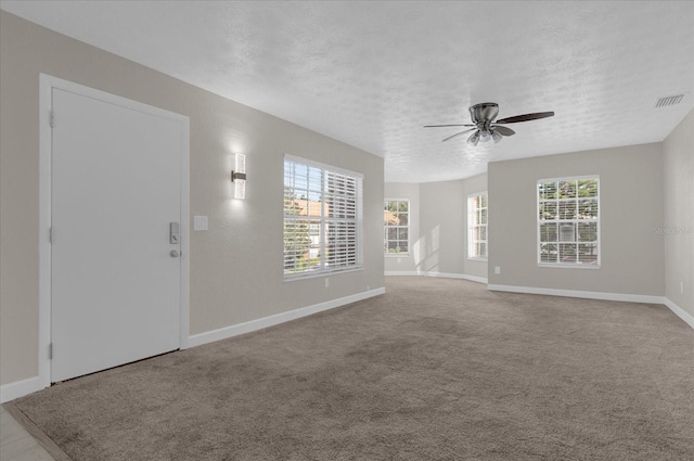 carpeted spare room with a textured ceiling and ceiling fan