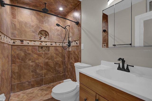 bathroom with tiled shower, vanity, and toilet