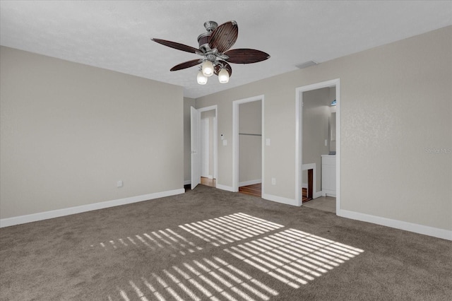 unfurnished bedroom with a spacious closet, a closet, ensuite bath, carpet flooring, and ceiling fan