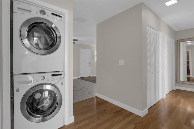 laundry room with wood-type flooring, stacked washer and dryer, and ceiling fan