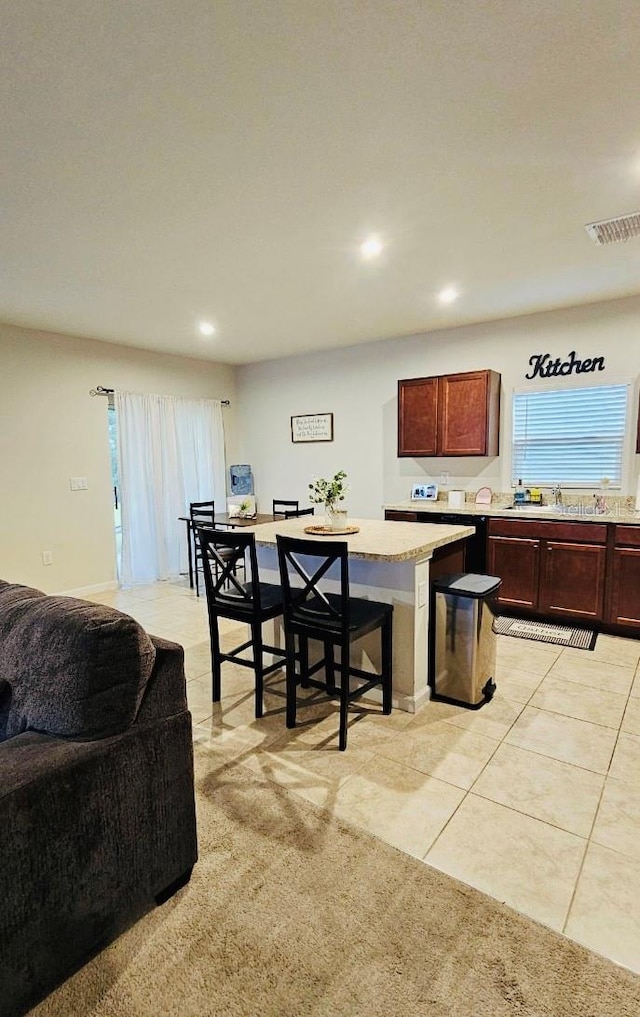 kitchen with light colored carpet, a center island, and sink