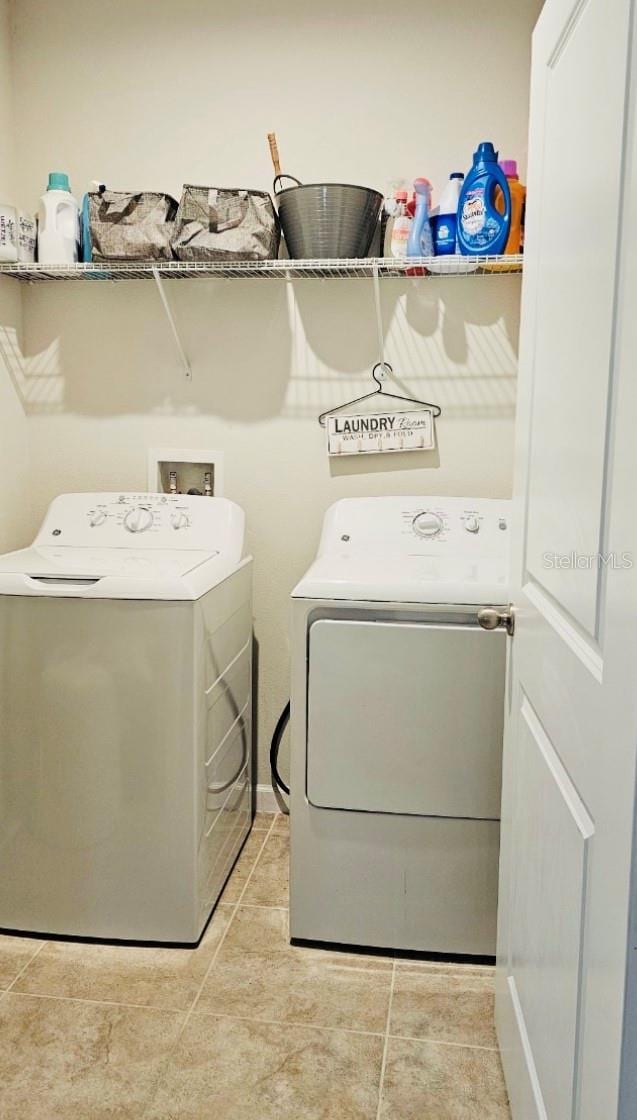 washroom with light tile patterned floors and washer and clothes dryer