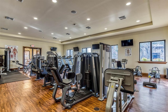 workout area with hardwood / wood-style flooring and a raised ceiling