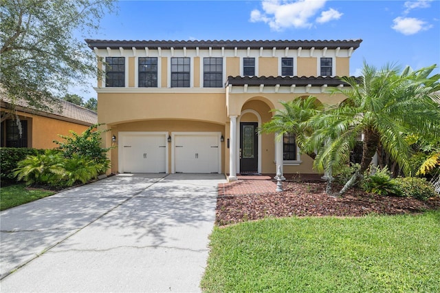 mediterranean / spanish house with concrete driveway, a tiled roof, an attached garage, and stucco siding